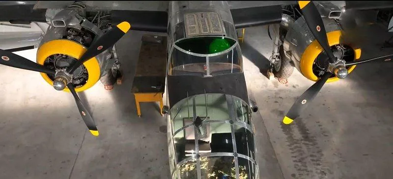 An overhead view of the B-25 Mitchell bomber, showing the cockpit and both engines with yellow propeller hubs.