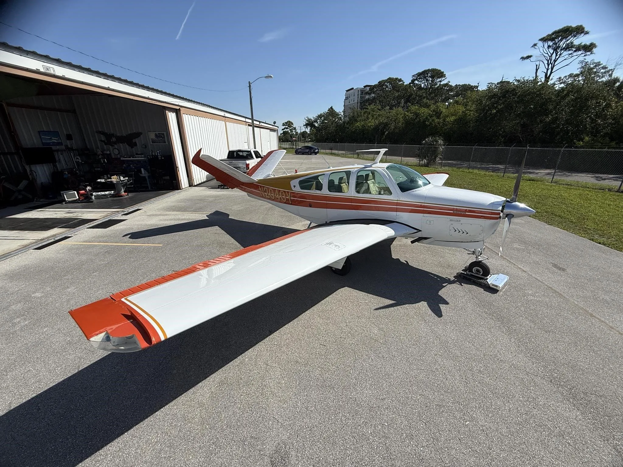 A white and orange single-engine aircraft, N2040Y, seen from the front-right, parked on an asphalt ramp.