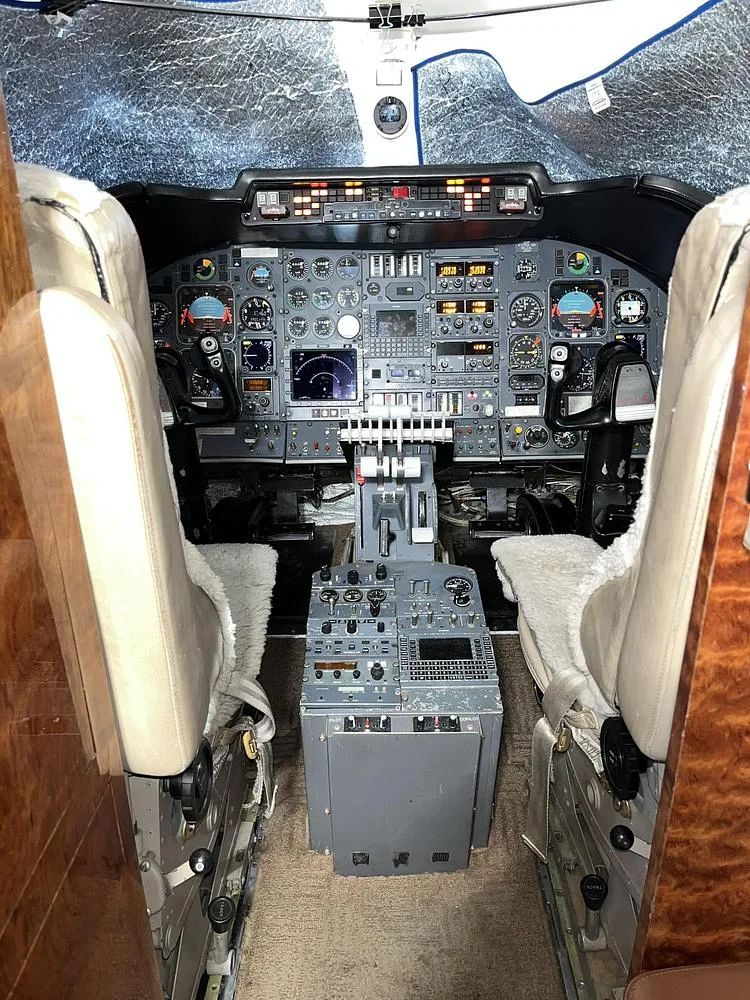 The cockpit of a private jet showing the instrument panel, flight controls, and pilot seats.