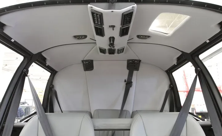 The interior of a Robinson R66 Turbine helicopter with gray seats and seatbelts.
