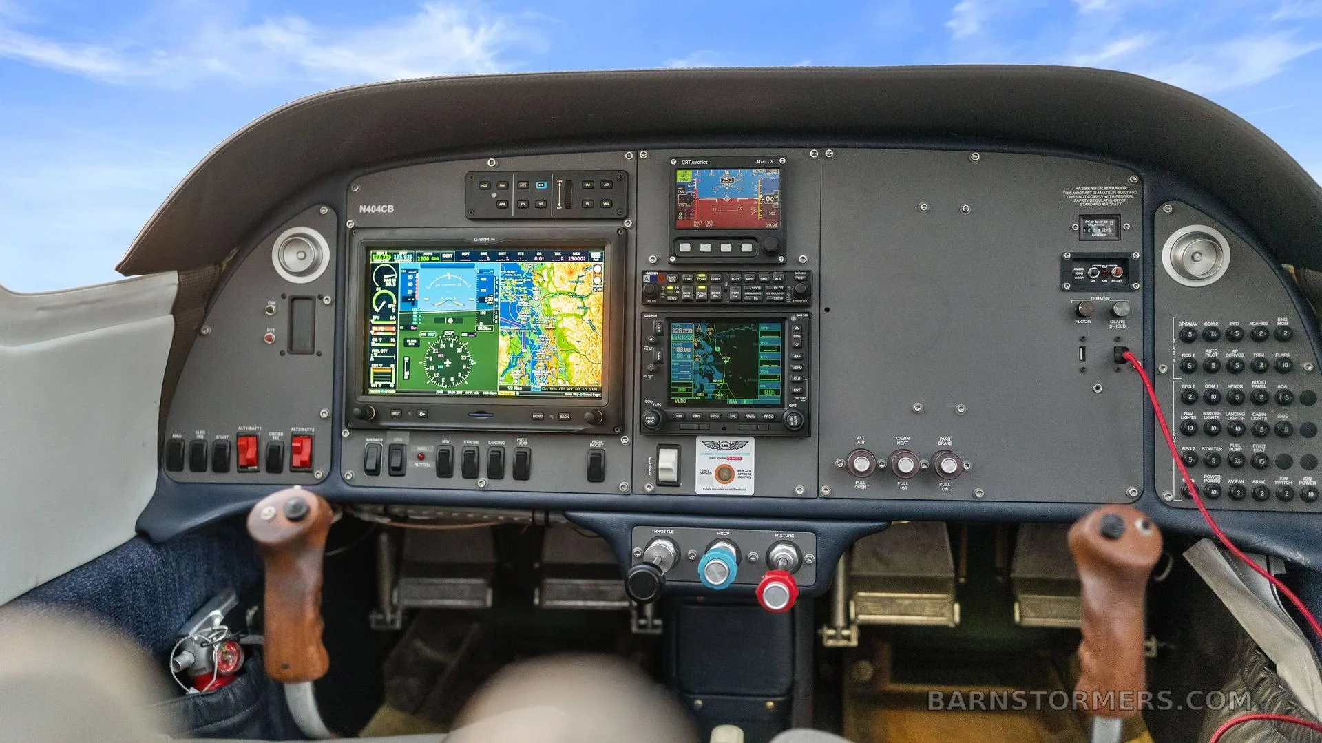 The cockpit instrument panel of the N404CB aircraft, featuring multiple Garmin displays and traditional controls.