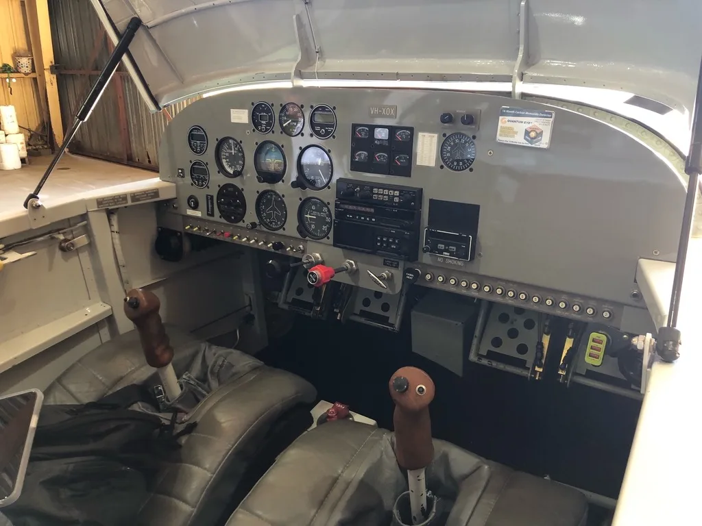 The cockpit of an RV-6A aircraft, showing the instrument panel, controls, and two grey seats.