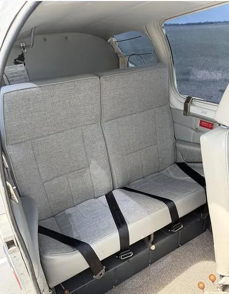 The aircraft's rear cabin with two grey fabric seats and black seatbelts.