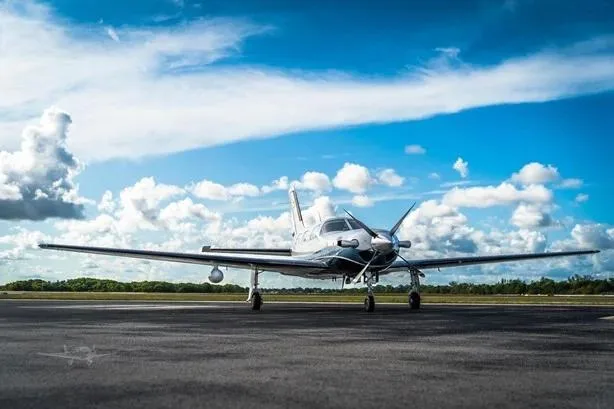 The white and blue Piper M500 (Meridian) aircraft, registration N724HA, seen from the front on a tarmac under a blue sky.