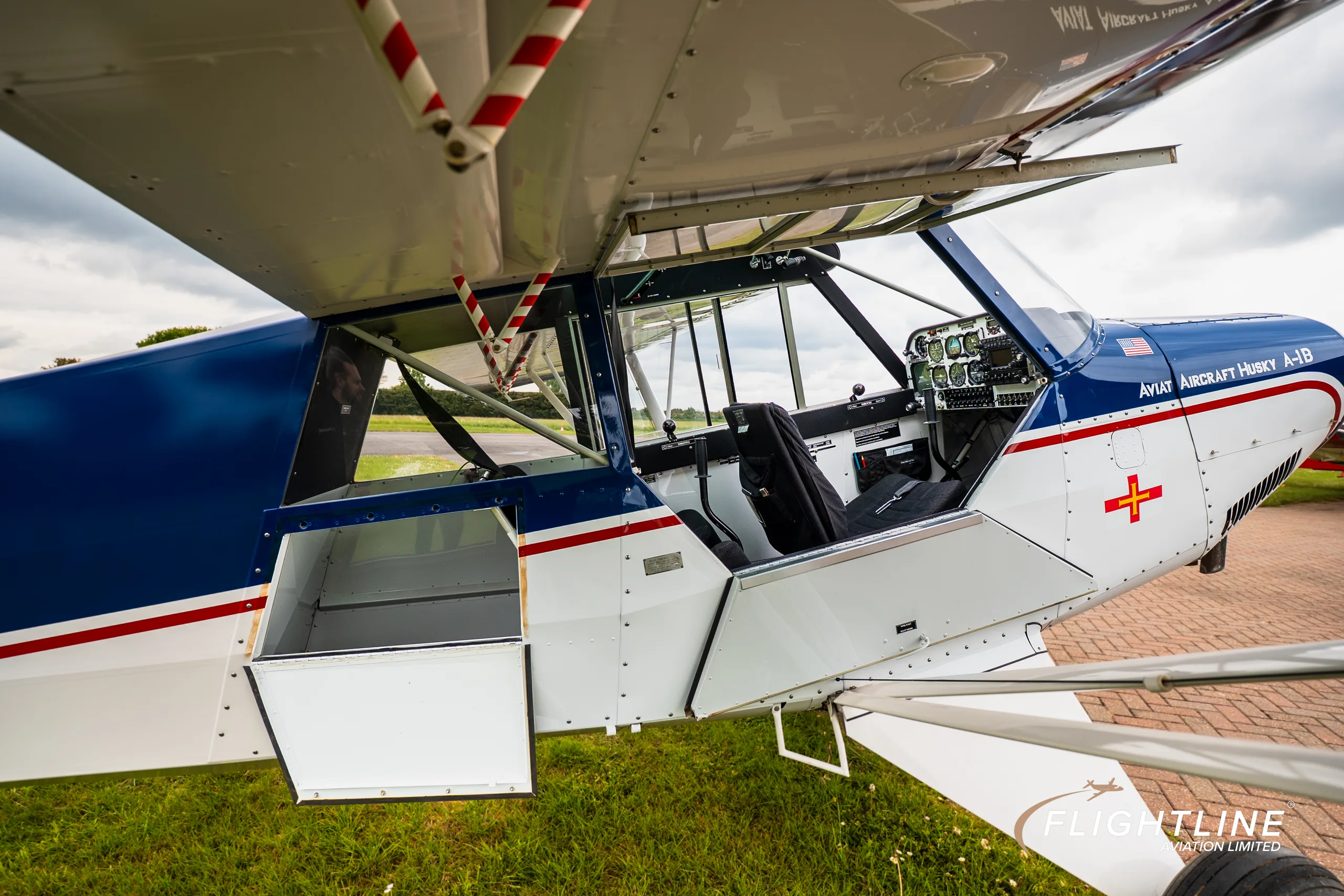 Side view of the blue and white Aviat Aircraft Husky A-1B (N78HB) with its doors open, showing the cabin and storage compartments.