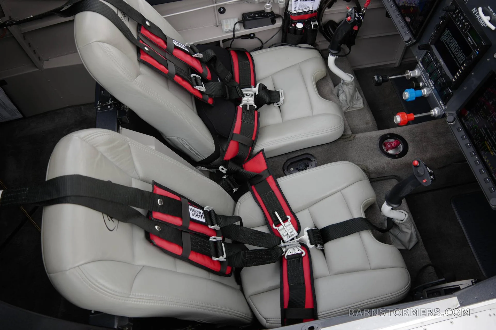 The gray leather seats with red and black harnesses in the cabin of a Vans RV-140MP aircraft.