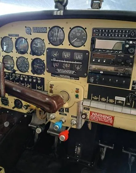 The full instrument panel and controls, including a yoke, in an aircraft cockpit.