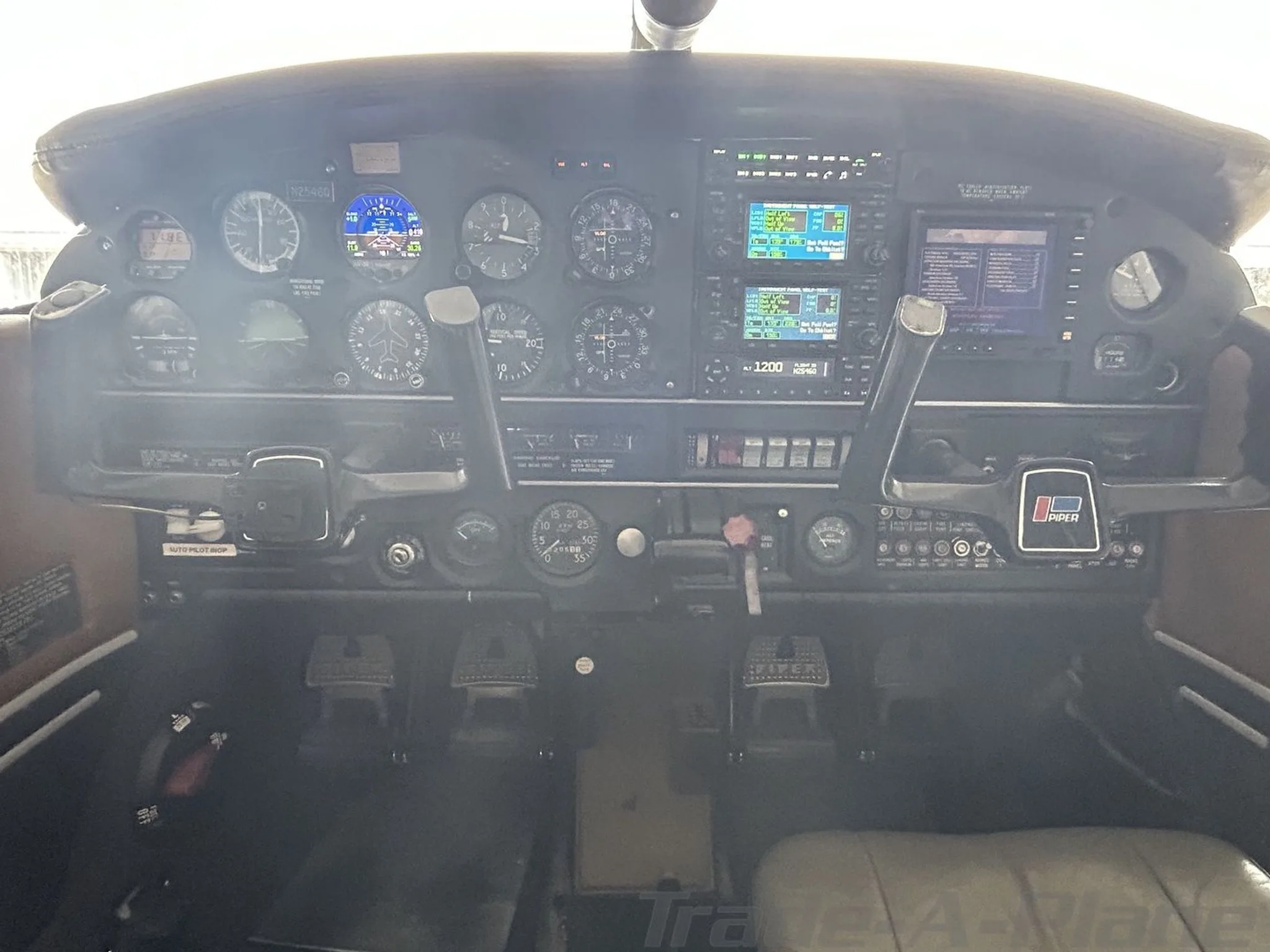 The cockpit instrument panel of a Piper aircraft, featuring analog gauges and modern digital displays.