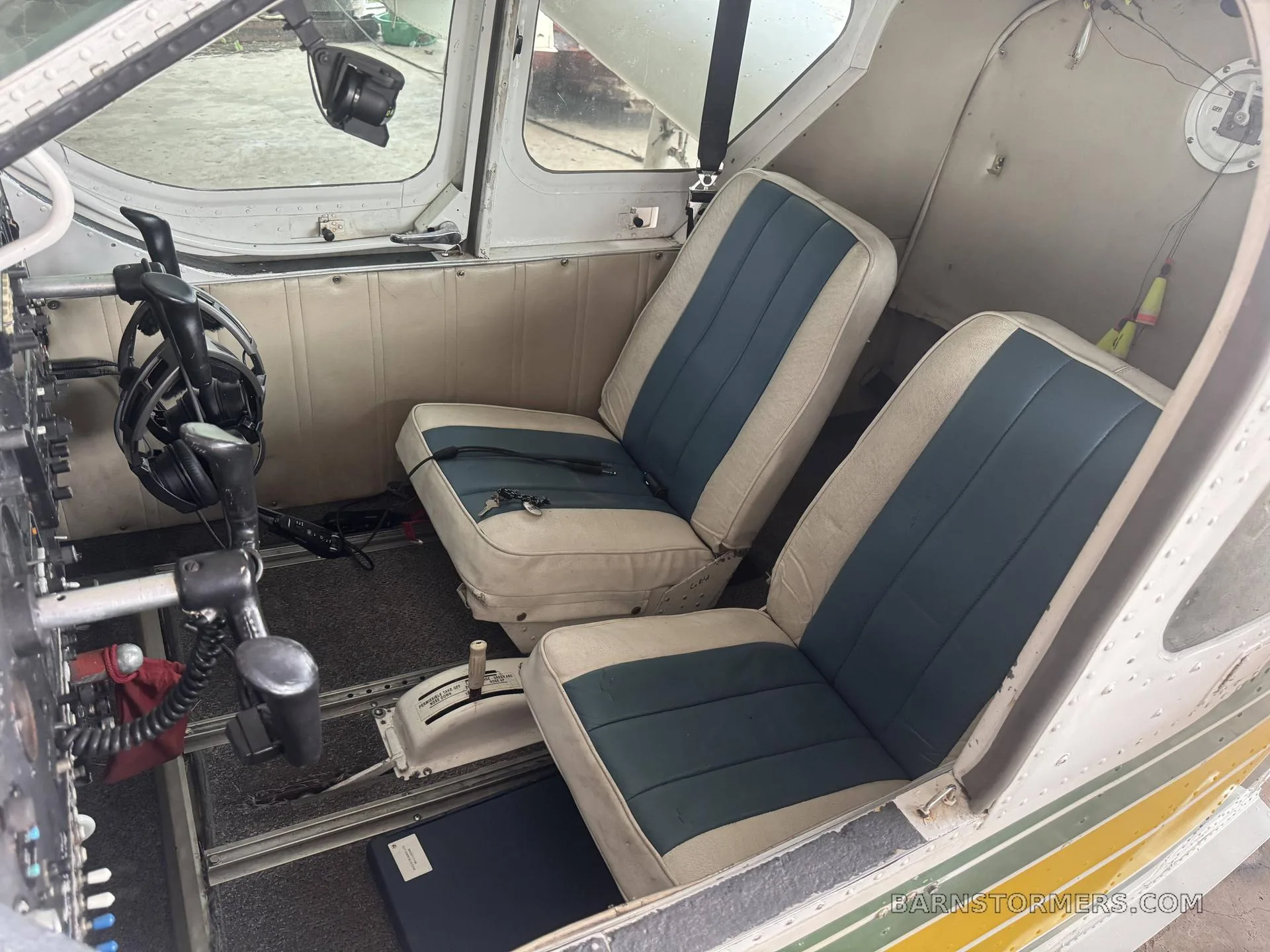 The interior of an aircraft cabin showing two front seats with blue and white upholstery.