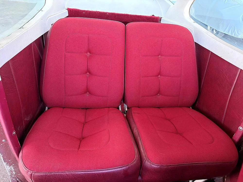 Close-up view of two red fabric and vinyl aircraft seats inside the cabin.