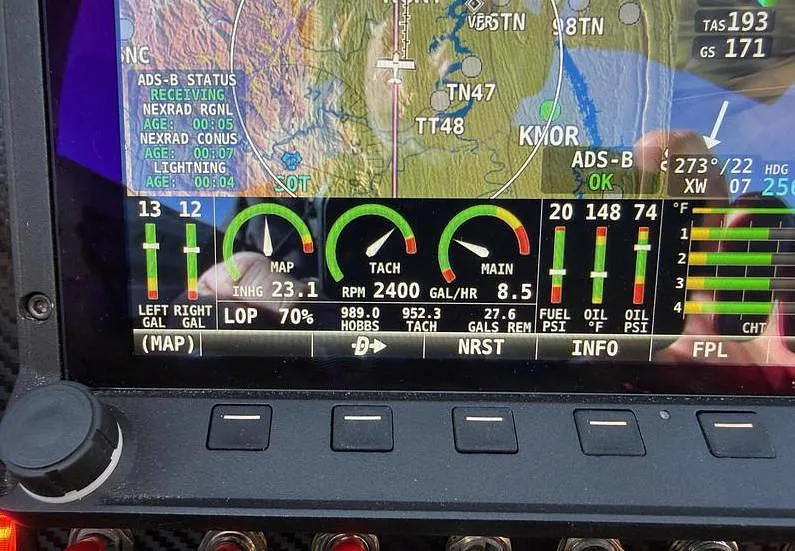 A close-up of an aircraft cockpit display showing navigation, engine parameters, and ADS-B status.