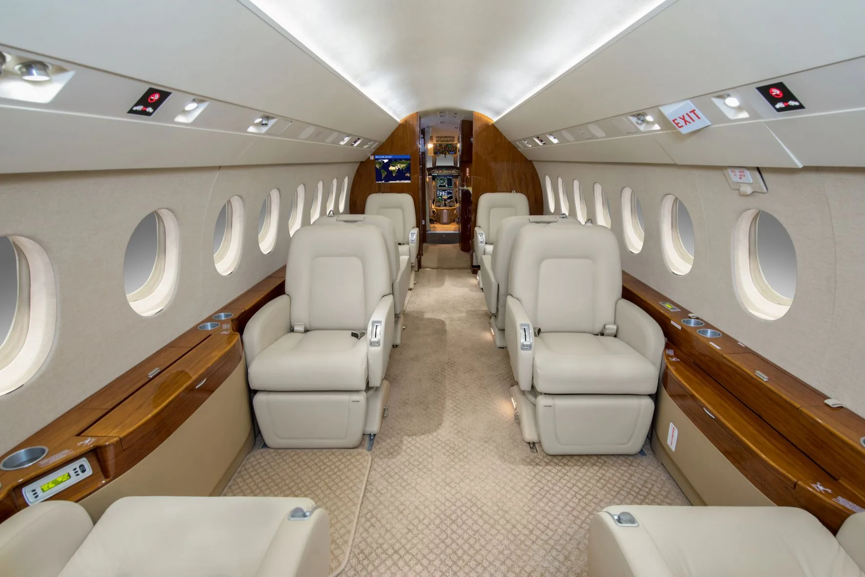 A luxurious aircraft cabin with light-colored leather seats and wood accents, looking towards the rear.