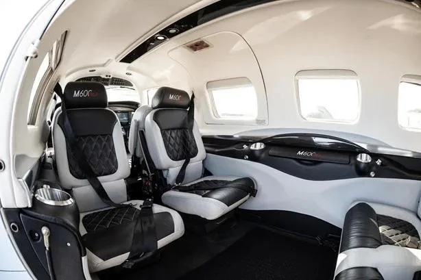 A wider view of the Piper M600 cabin interior, showing two rows of black and grey quilted leather seats.