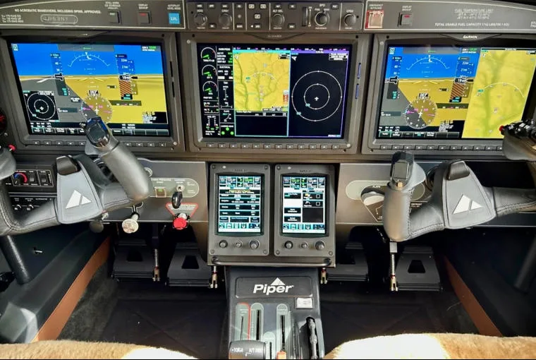 The cockpit of a Piper M600 SLS, featuring multiple glass displays, yokes, and throttle quadrant.