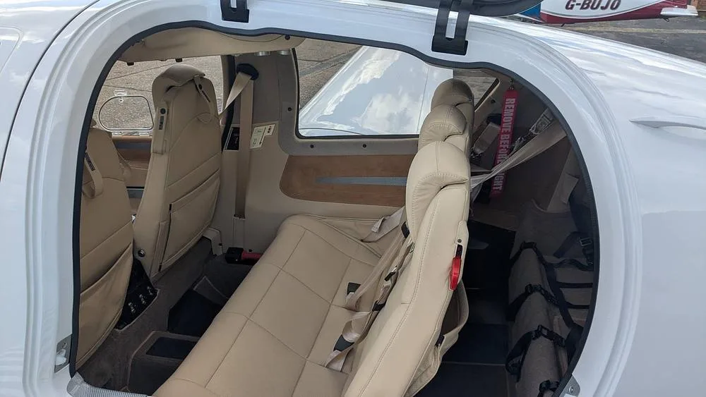 The beige leather interior cabin of a small aircraft, showing the rear seats and cargo area.