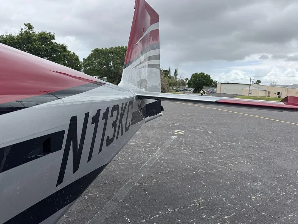Close-up view of the tail section of the N113KC aircraft, showing its red, silver, and black paint scheme and registration.