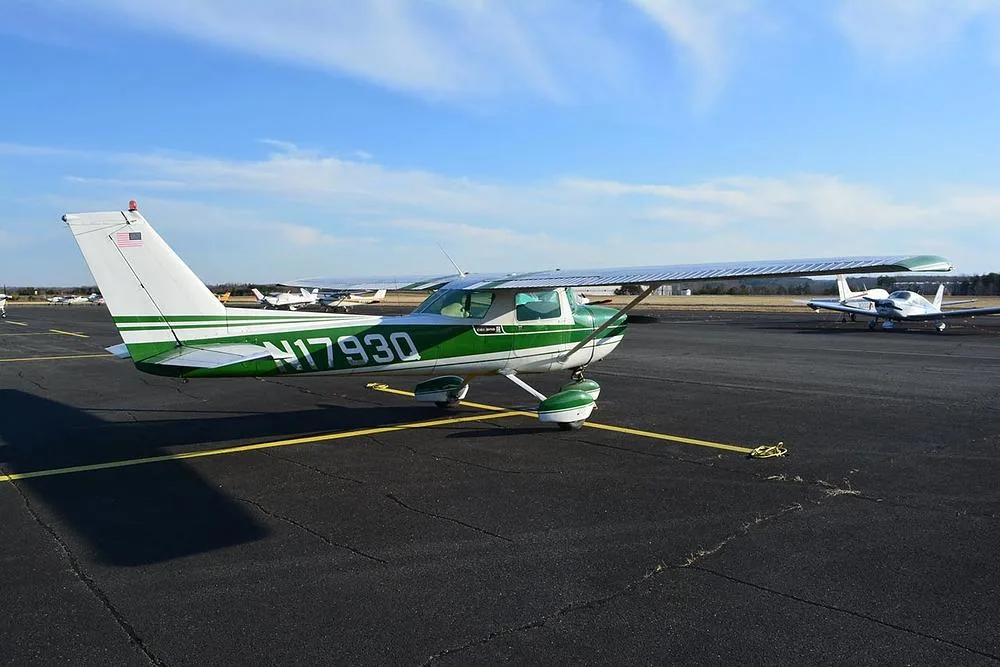 A rear-quarter view of a green and white Cessna 172 aircraft, registration N1793Q, parked on an airport tarmac.