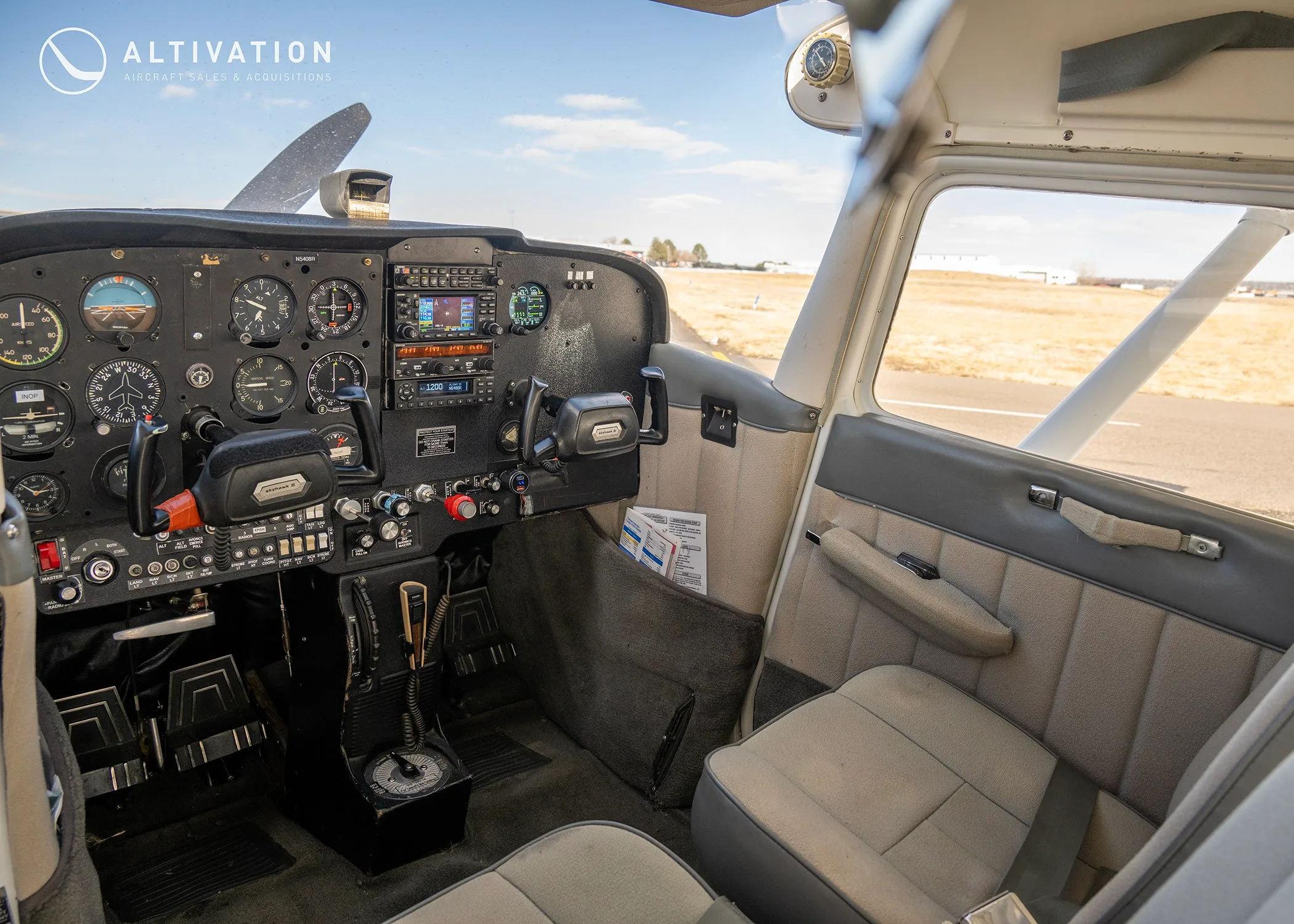 The cockpit of a Cessna 172, showing the instrument panel, yokes, and front seats.