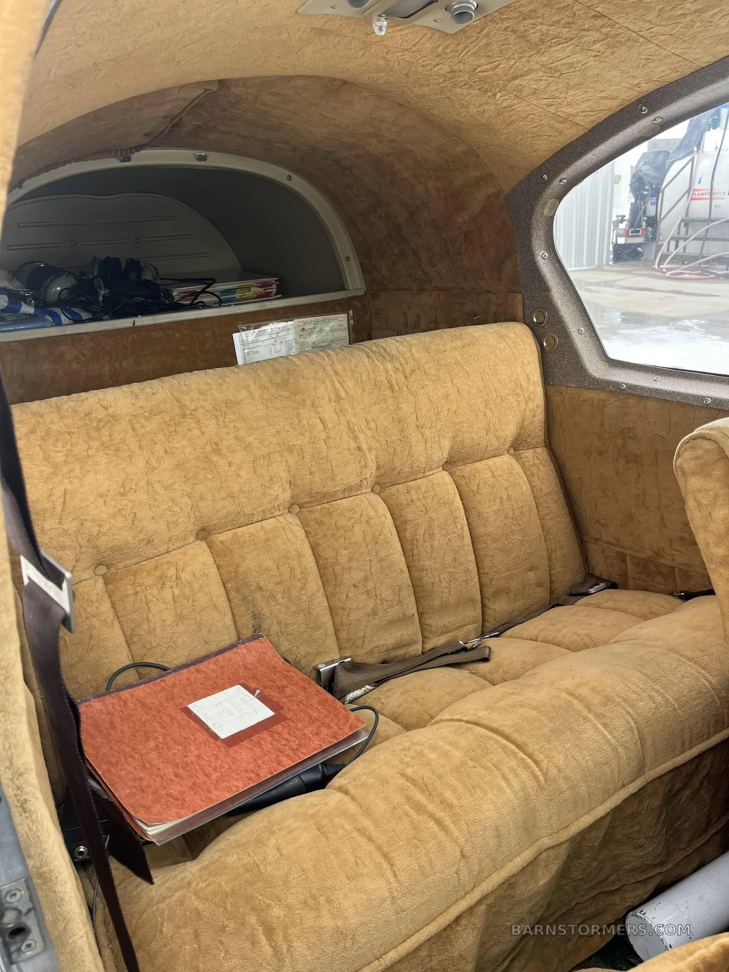 The aircraft's interior features tan upholstered rear seats and a small storage area.