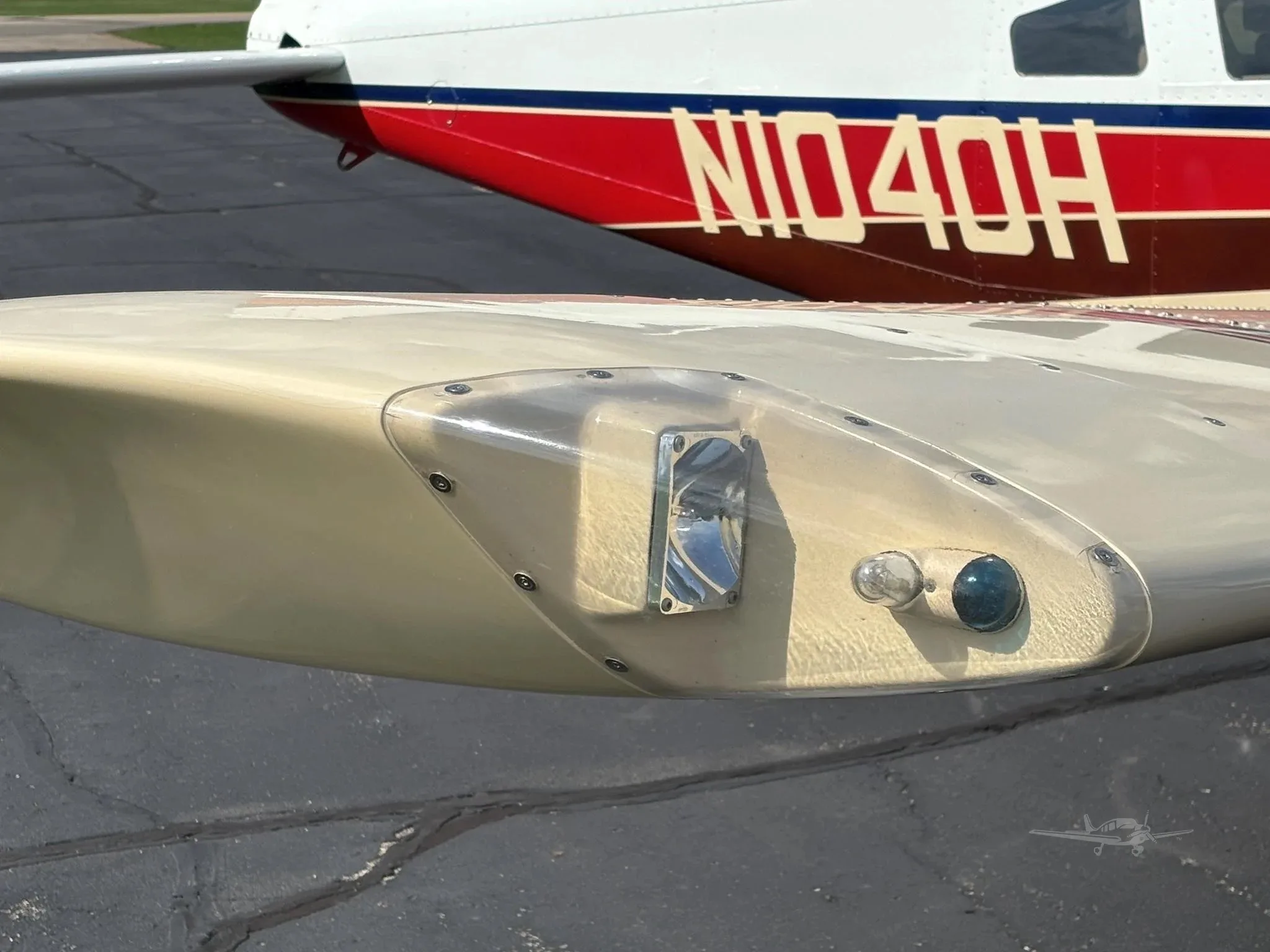 A close-up of the wingtip light and the "N1040H" registration on the tail of a white and red aircraft.