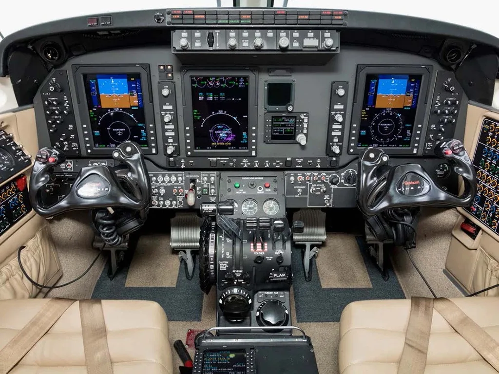 A detailed view of a modern aircraft cockpit with multiple digital displays and control yokes.