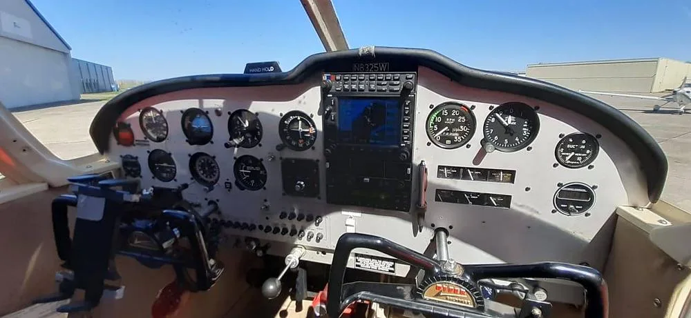 The cockpit of a red Piper Cherokee 180 (N8325W) showing the instrument panel and controls.