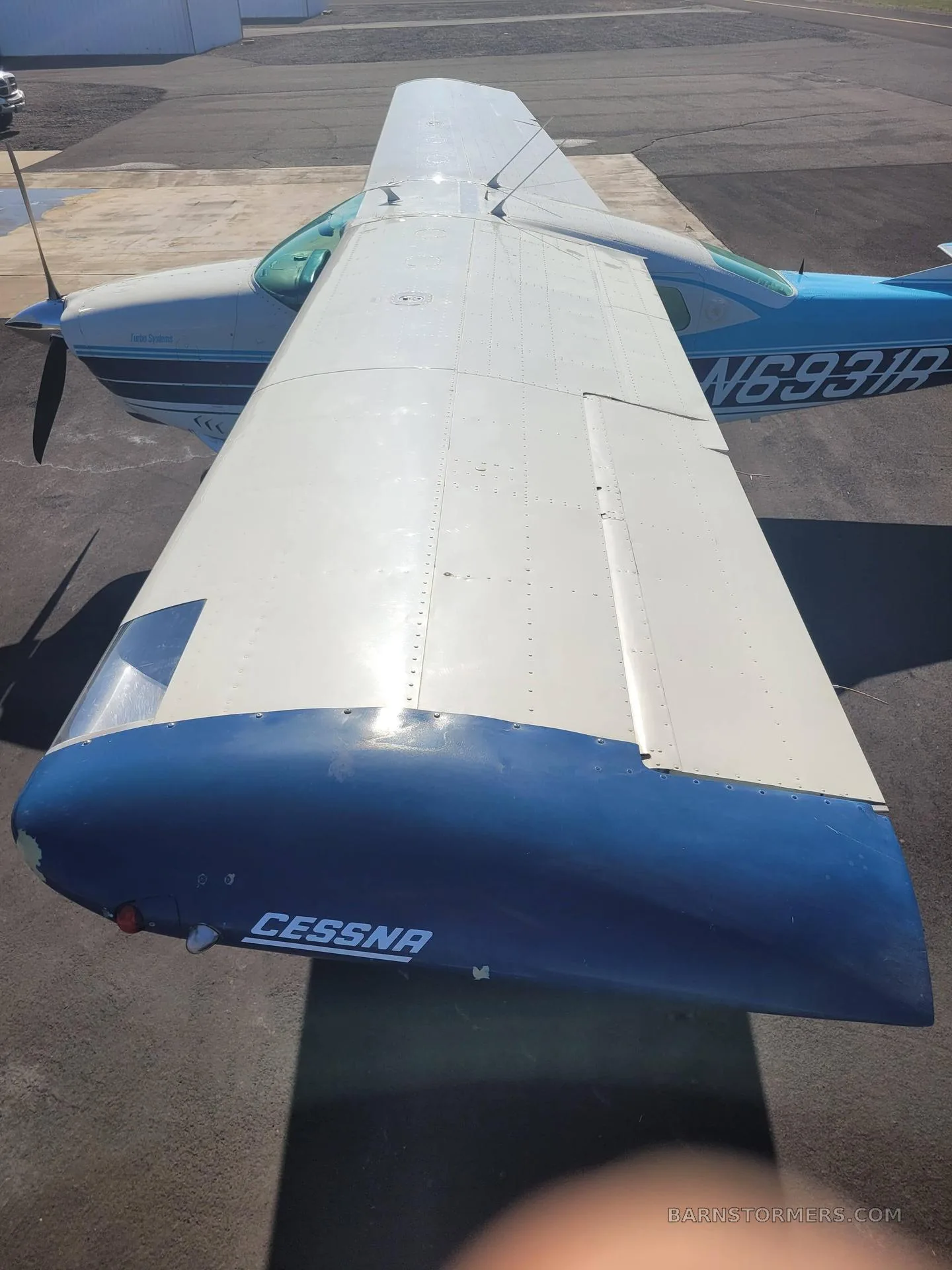 An overhead view of the white wing and blue wingtip of a Cessna T206H Turbo Stationair (N6931R).