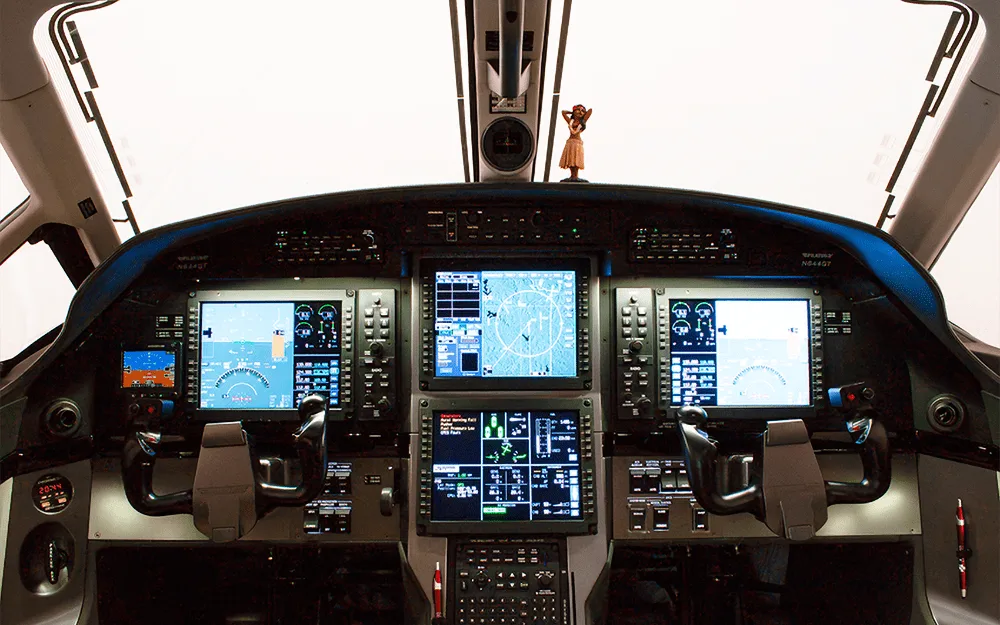 The cockpit of a Pilatus PC-12 NGX features multiple large digital displays and control yokes.