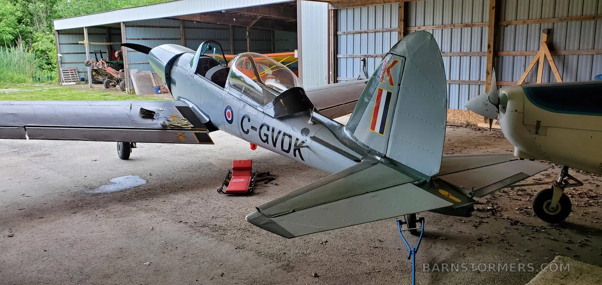 A light grey single-engine aircraft with Canadian registration C-GVDK parked partially inside a hangar.