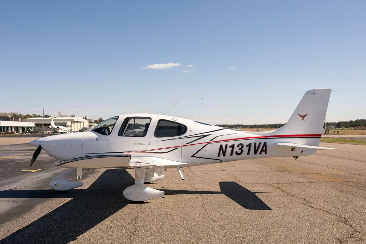A white Cirrus SR22 aircraft with red and black accent stripes, tail number N131VA, parked on an airfield.