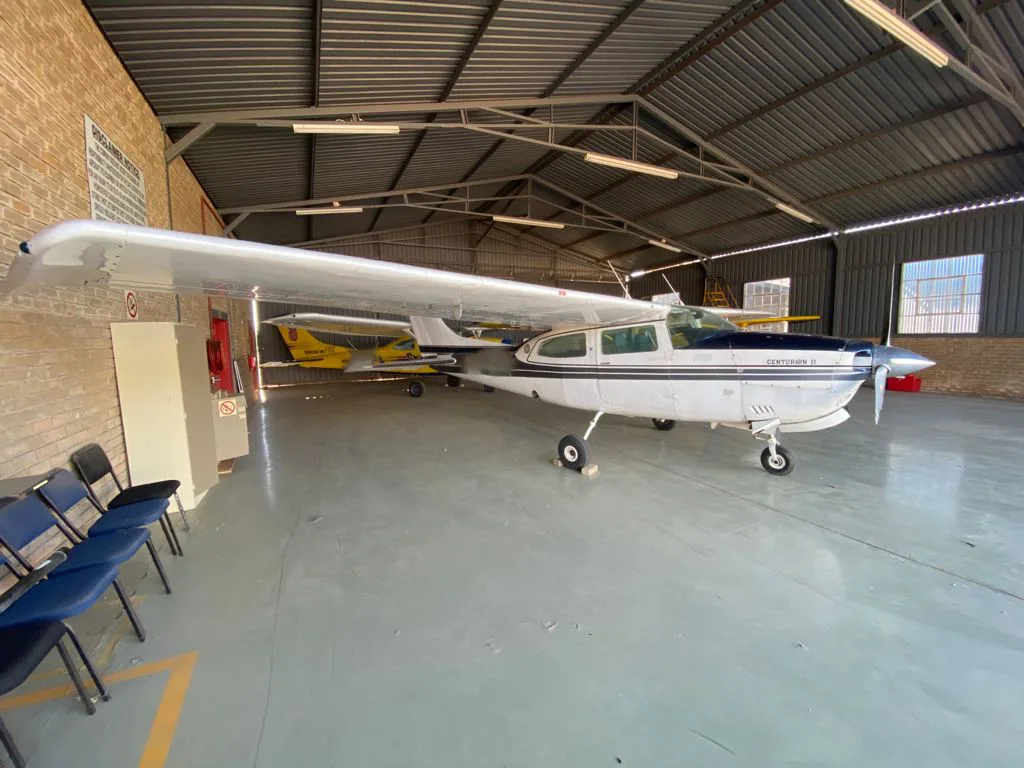 The cockpit of a light aircraft with dual yokes, a complex instrument panel, and tan leather seats.