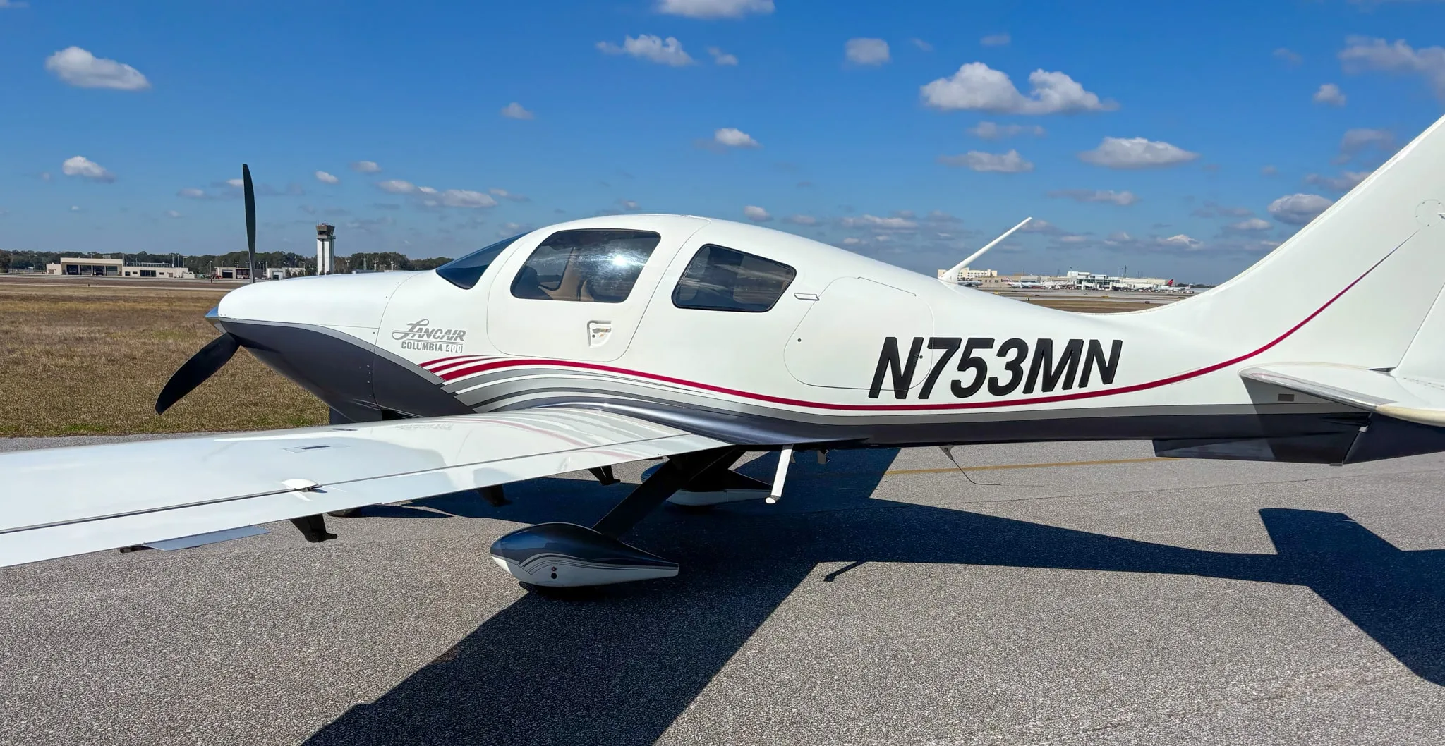Close-up side view of the Lancair Columbia 400 N753MN showing its white, grey, and red paint scheme.