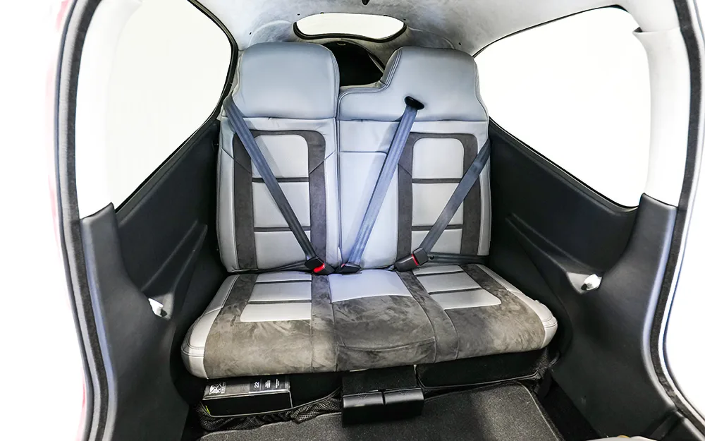 The gray and black leather rear bench seat of a Cirrus SR22 aircraft, with two seatbelts visible.