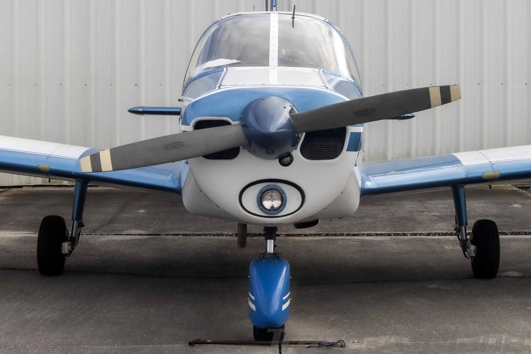 A head-on view of the blue and white Piper Cherokee N586 showing its propeller and landing light.