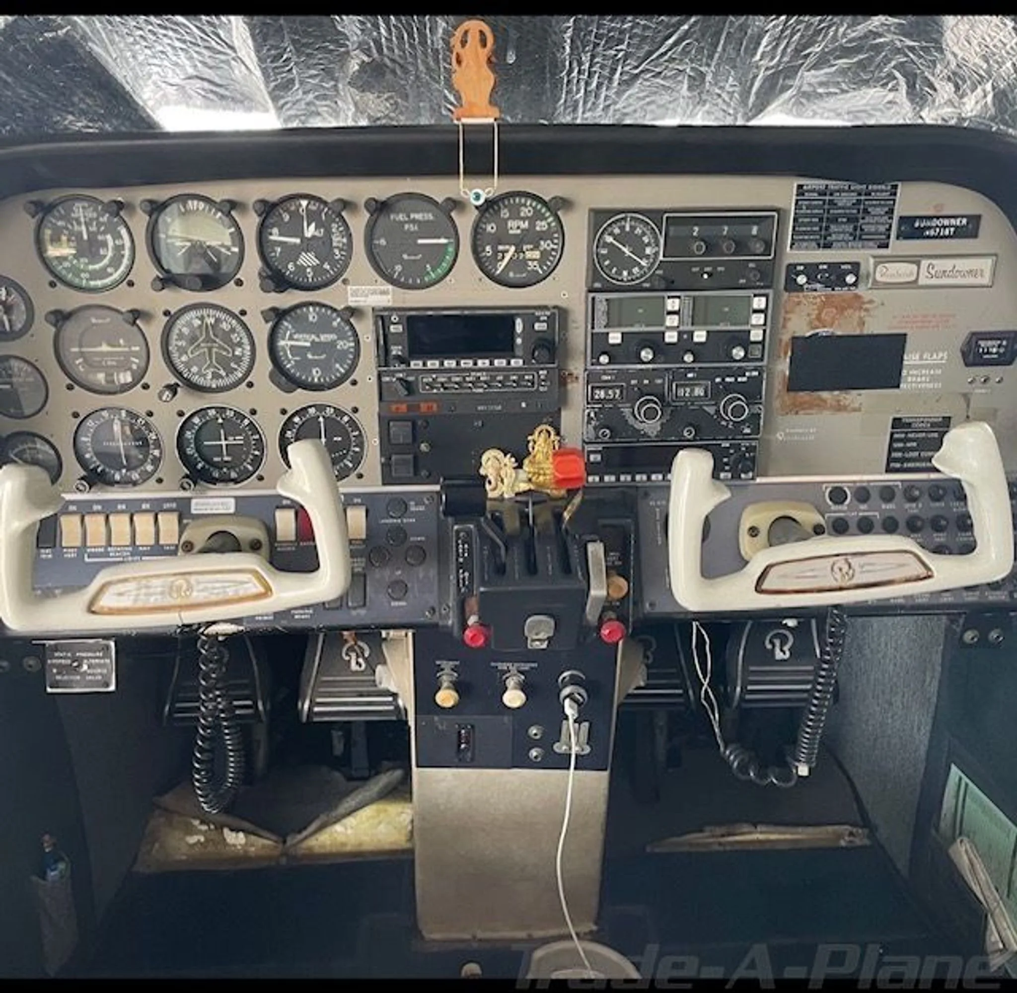 The cockpit of a Beechcraft Sundowner, showing the instrument panel, center console, and two control yokes.