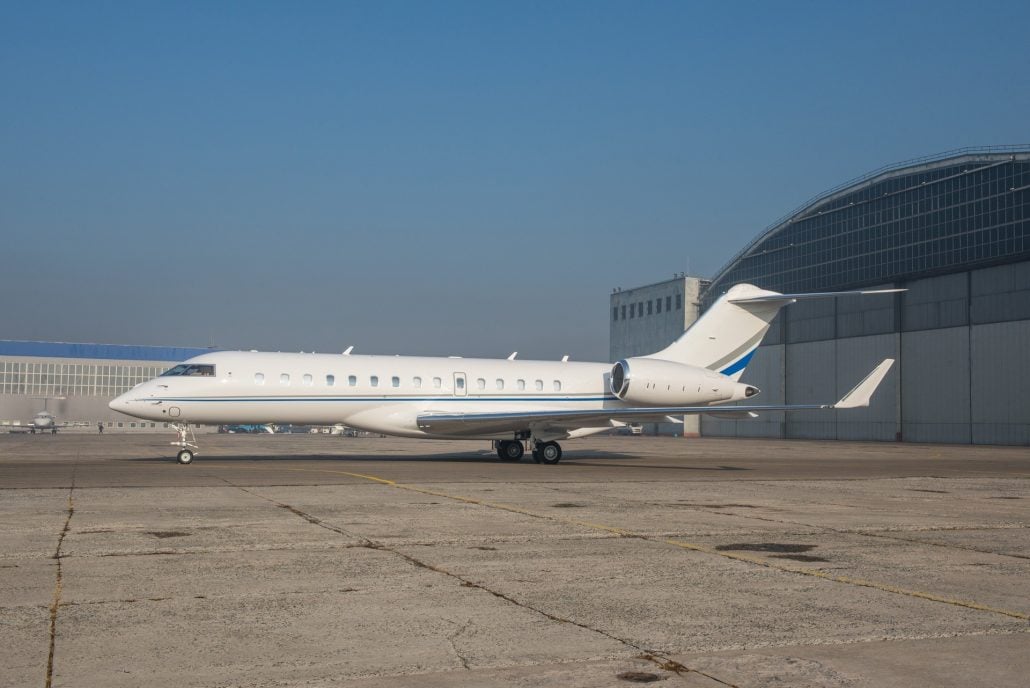 A Bombardier Global on the tarmac in front of a hangar.
