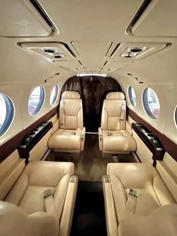A view of the aircraft's beige leather cabin interior with four passenger seats and large windows.