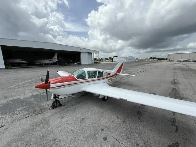 A wide-angle view of a white and red single-engine aircraft, N2667B, on an airport tarmac.