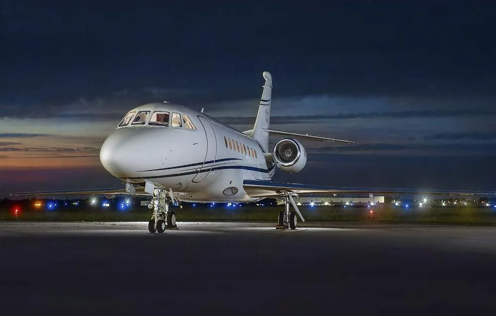 A Dassault Falcon 2000 business jet, registration N192HA, viewed from the front at night on an airfield.
