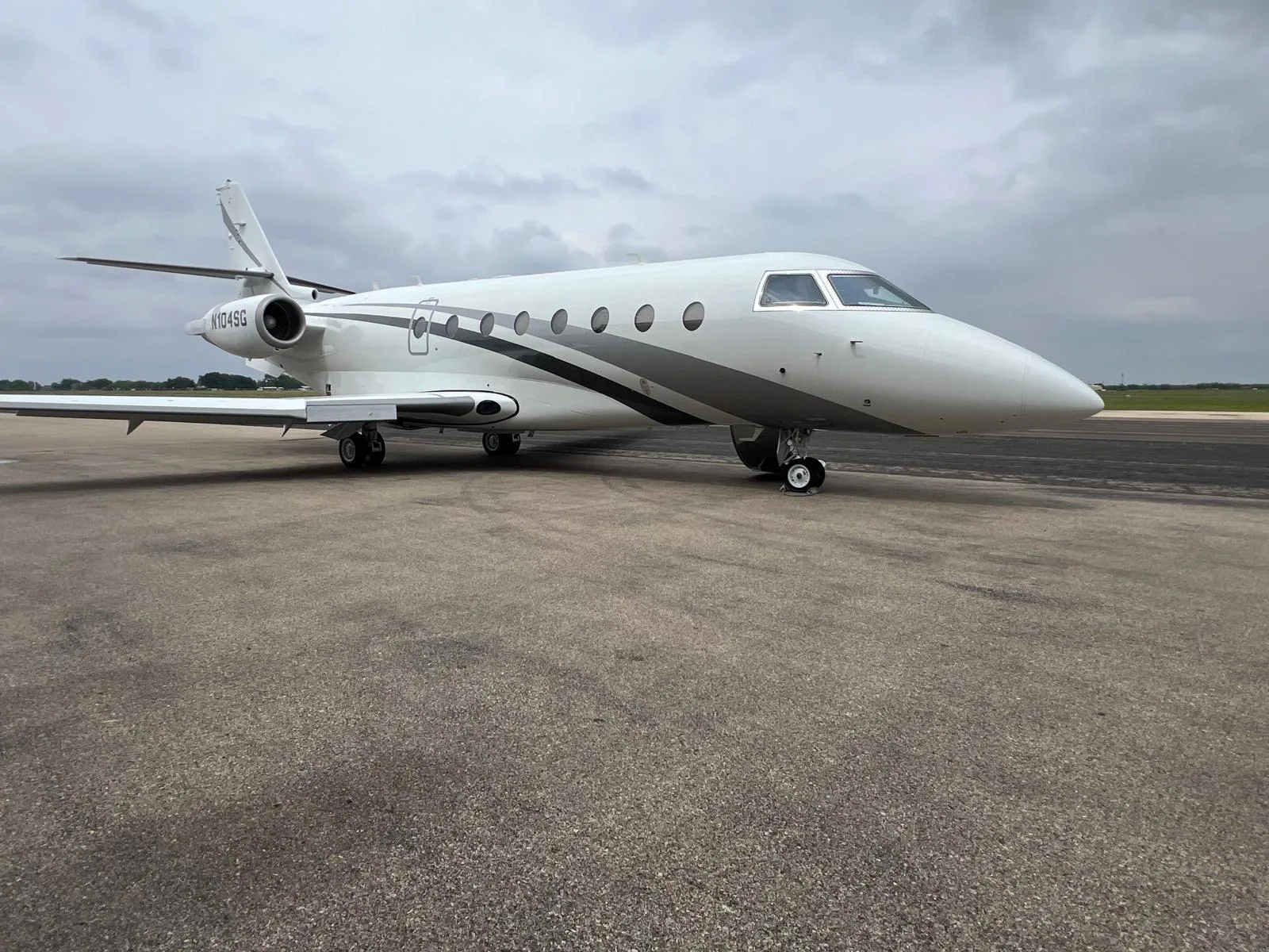 A white and gray jet with tail number N104SG sits on the tarmac.