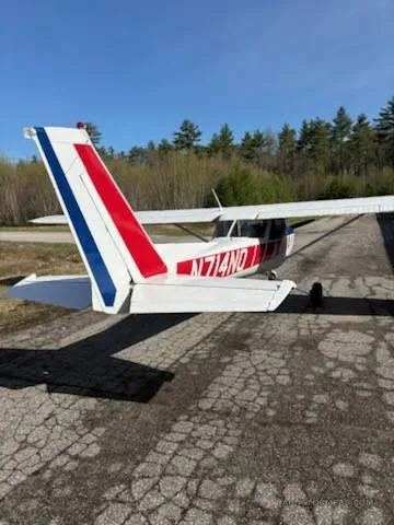 Rear view of a white, red, and blue Cessna-style aircraft parked on a cracked tarmac.