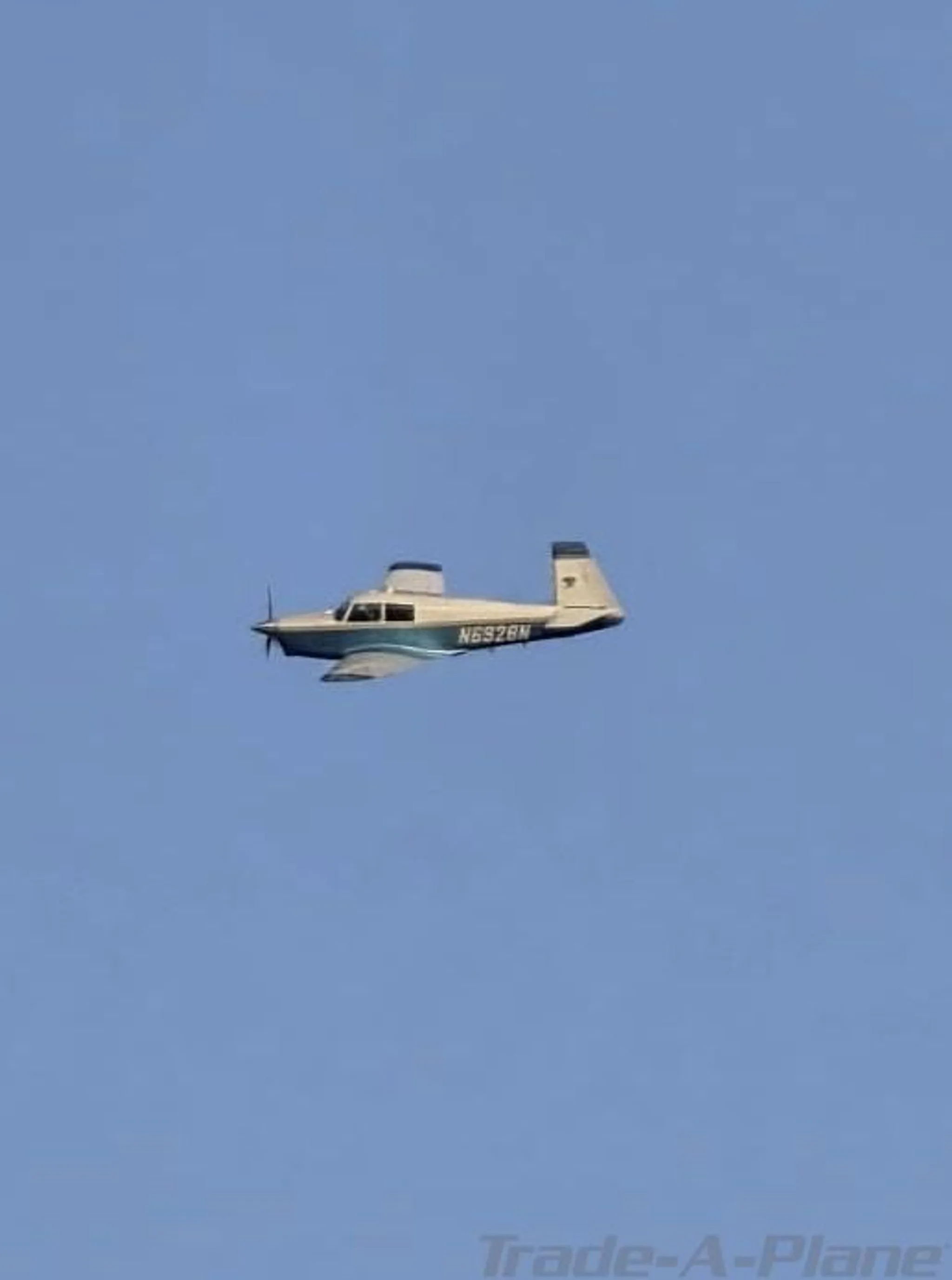 A light blue and white single-engine aircraft, N6928N, flying against a clear blue sky.
