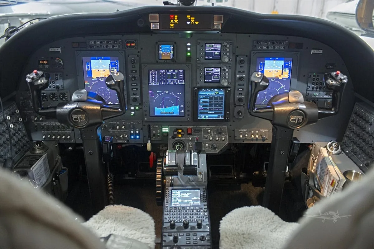 The cockpit of a modern business jet, featuring multiple glass displays and control yokes.