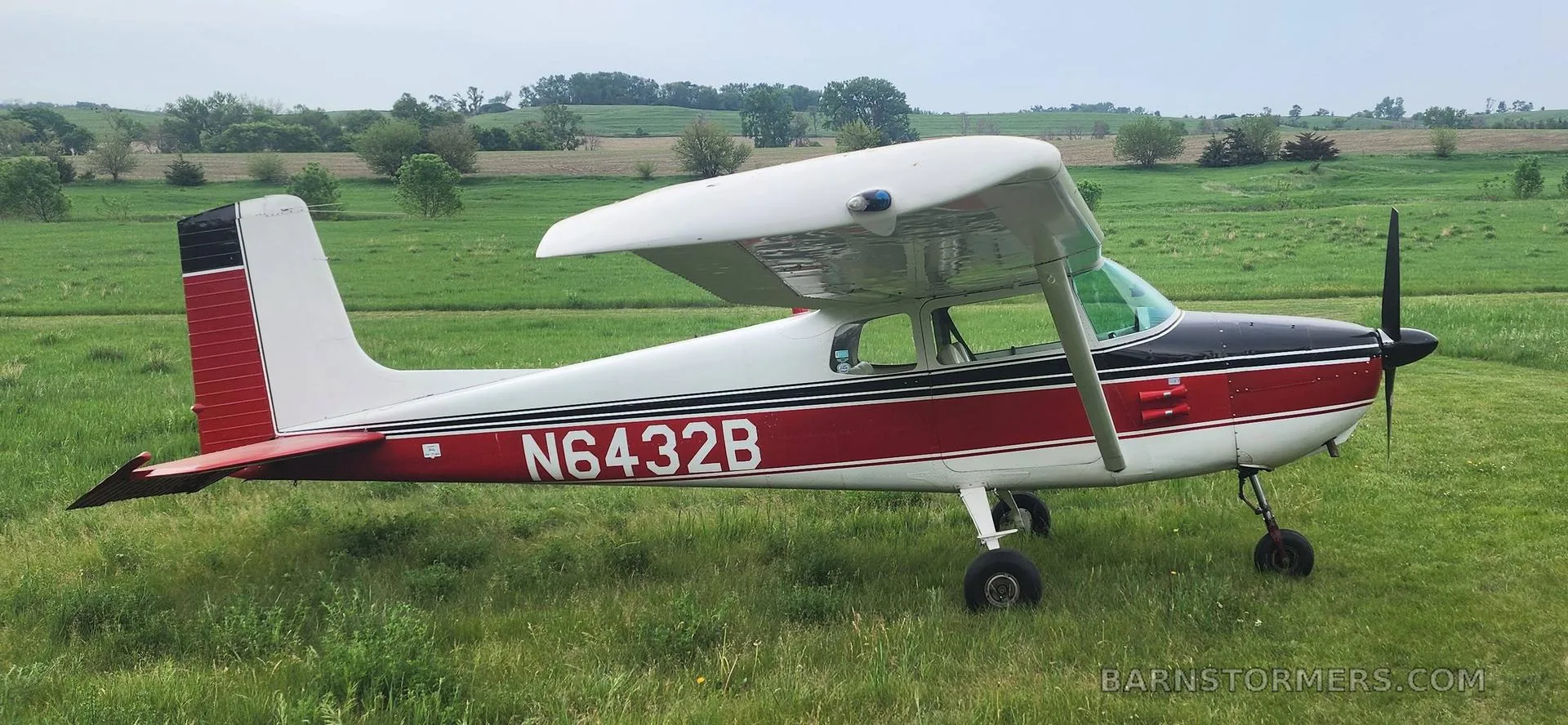 A white and red Cessna 172 with registration N6432B parked on a grassy field.