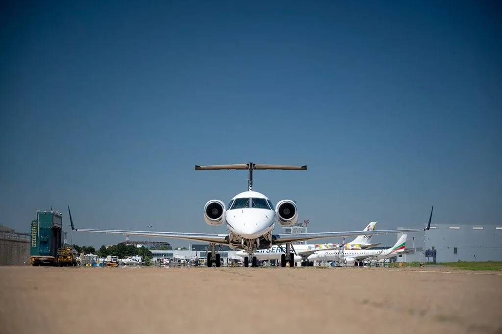 A head-on view of a white and black Embraer Legacy 600 business jet with registration YU-PAA on a tarmac.