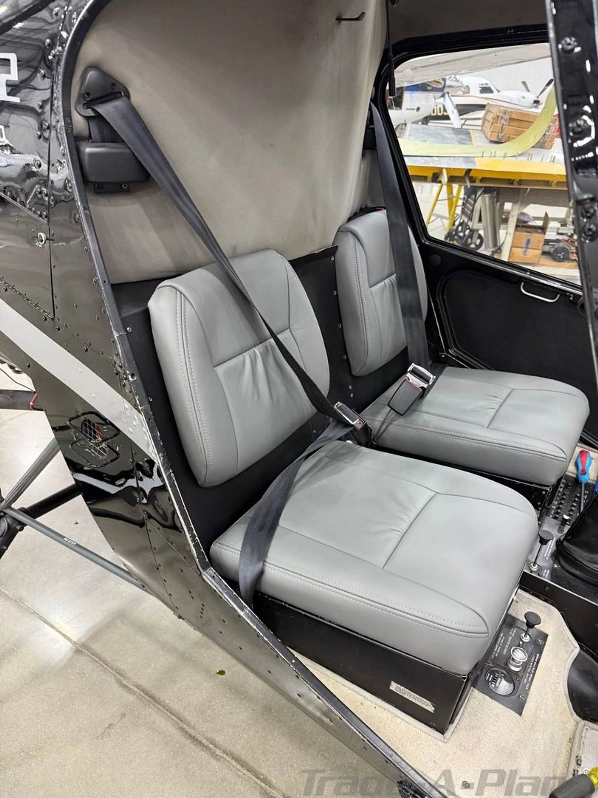 The two grey leather seats in the cabin of the Robinson R22 Beta helicopter.
