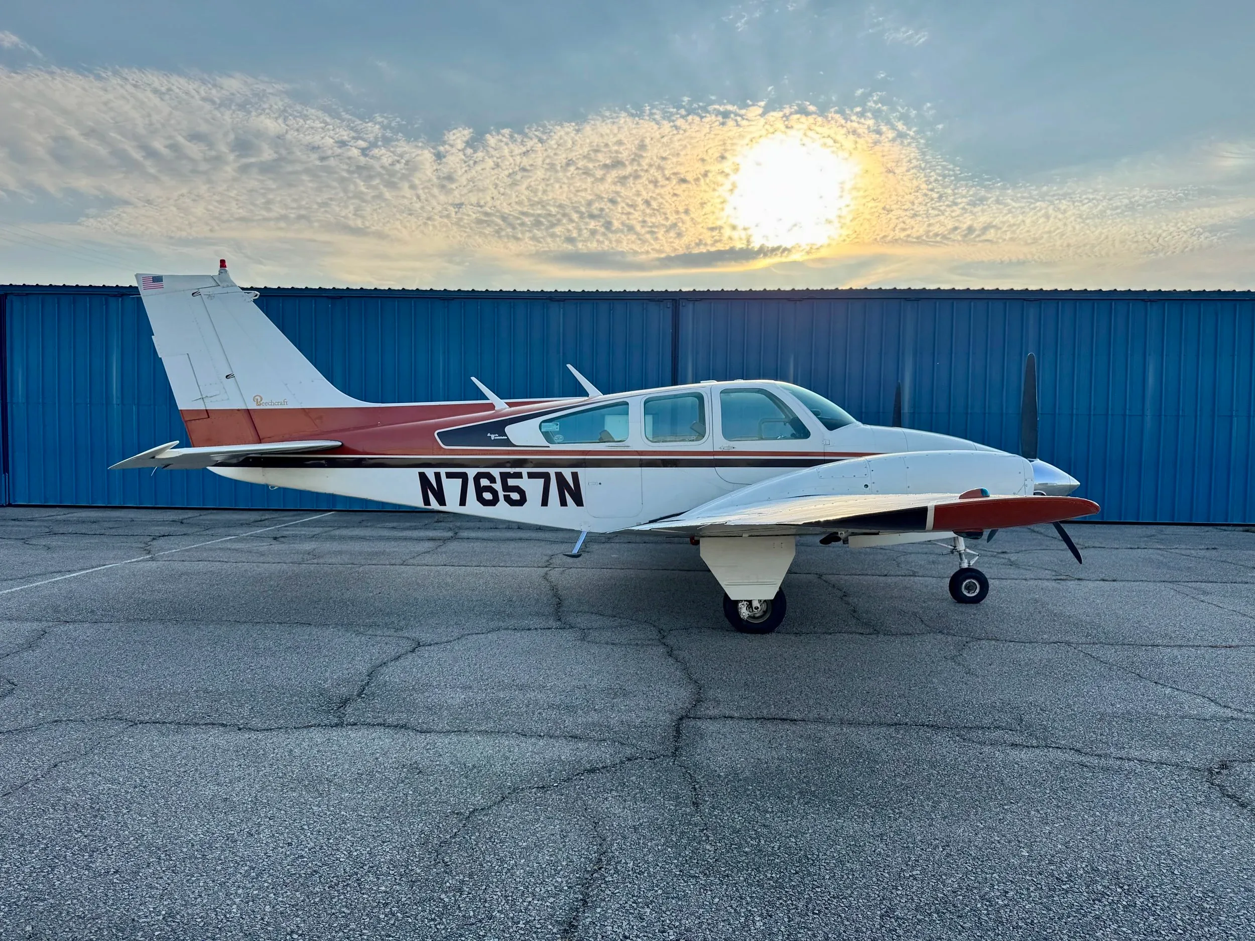 A Beechcraft Baron B55 aircraft with a white and brown paint scheme parked on the tarmac.