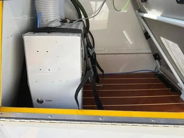 An internal compartment of the aircraft shows a silver equipment box secured with straps on a wooden floor.