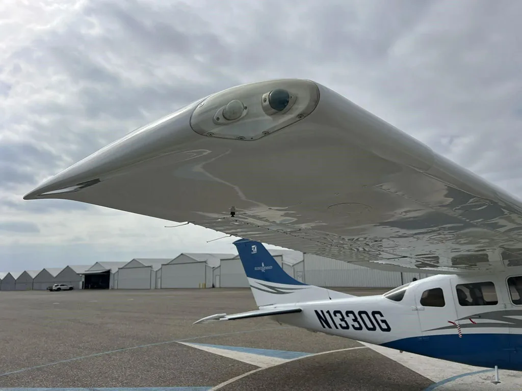 Close-up view of the right wingtip of a white and blue Cessna Stationair TC (N1330G) with landing lights.