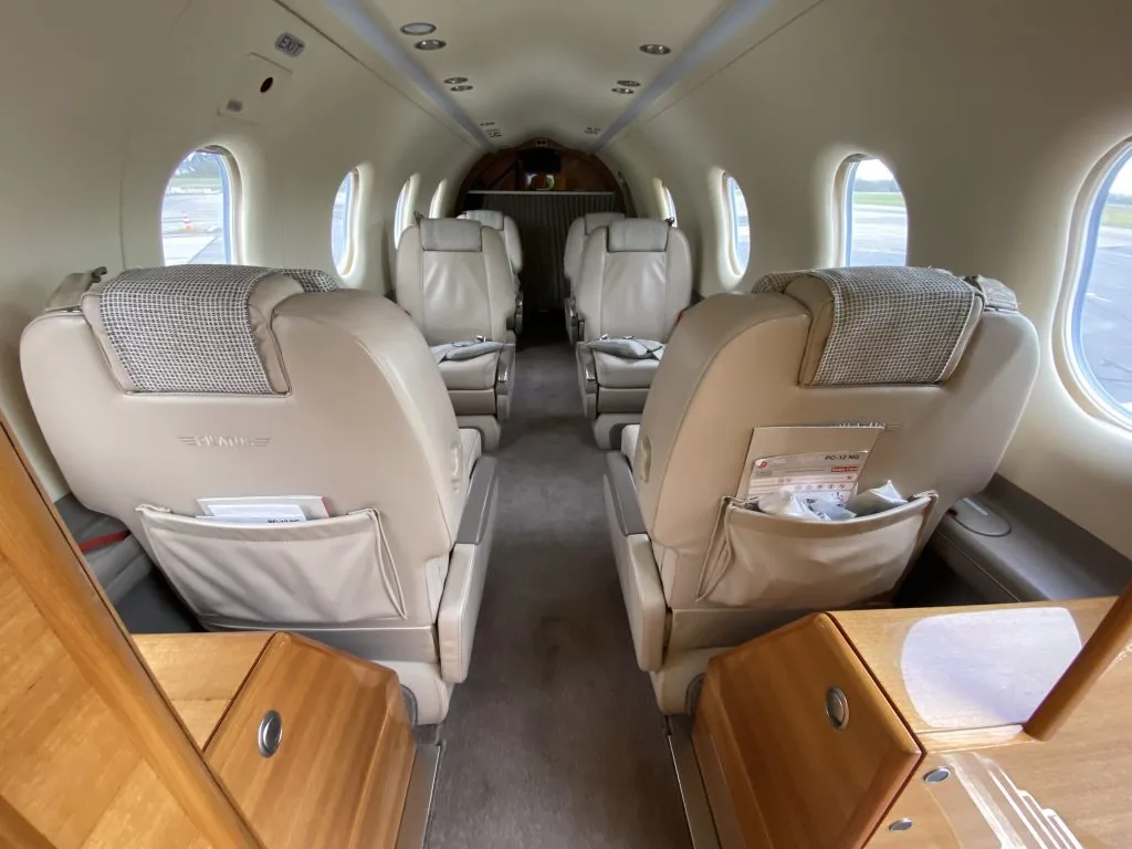 The beige leather interior cabin of an aircraft with four passenger seats visible, facing each other.